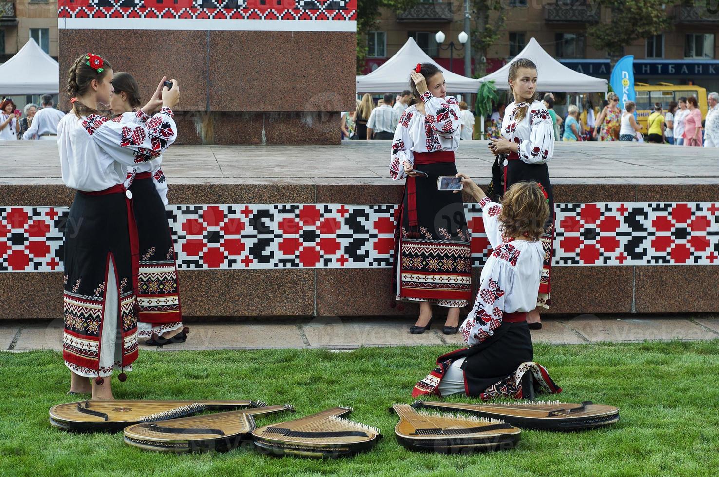 Young girl musicians in traditional Ukrainian clothes with embroidery make selfie on a mobile phone photo