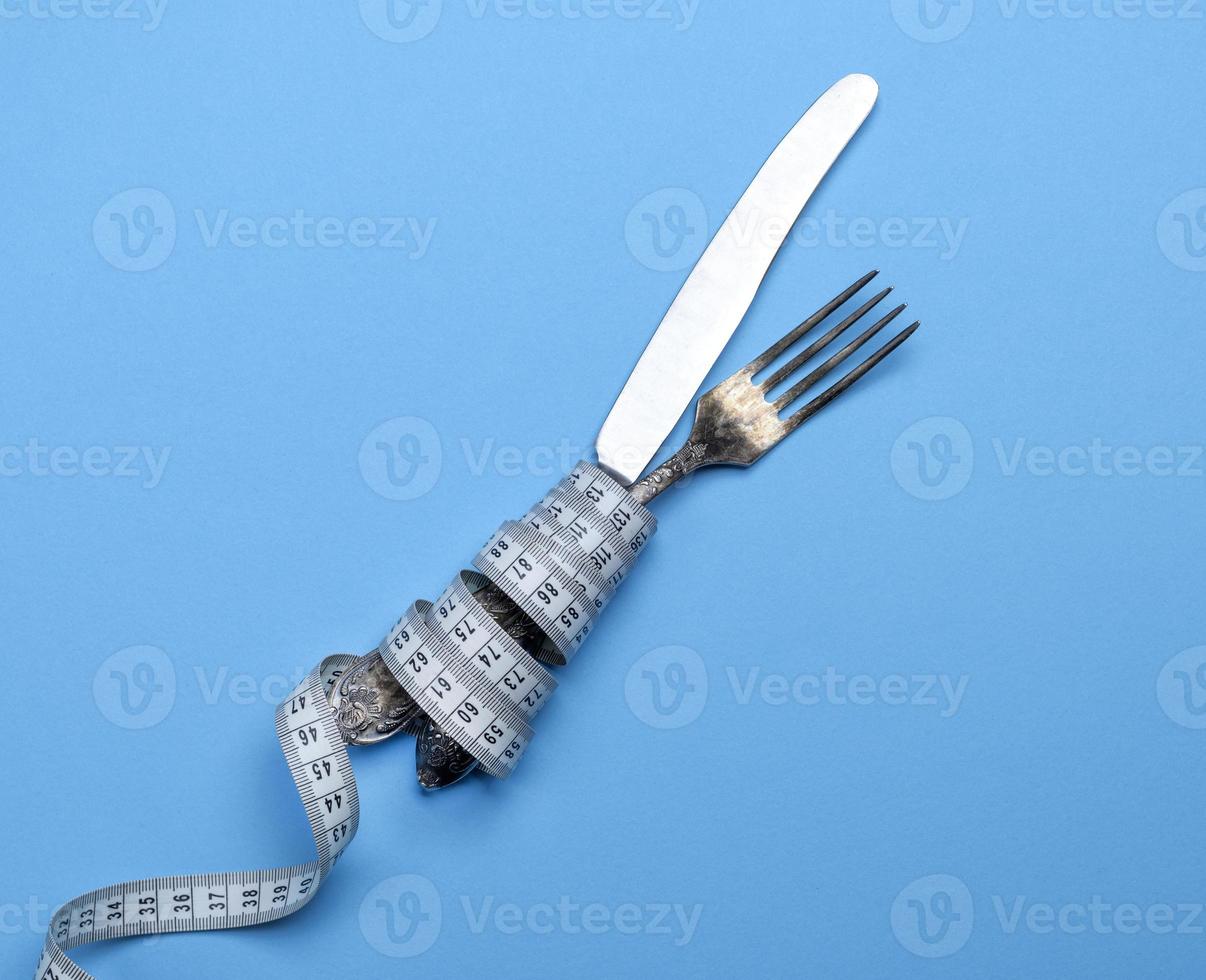tenedor y cuchillo de hierro envueltos en una cinta métrica foto