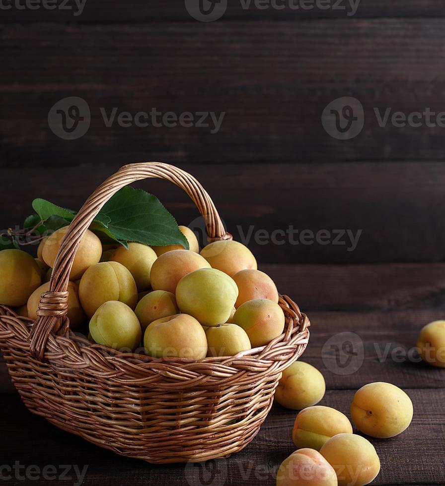 apricots in a brown wicker basket on a wooden table photo