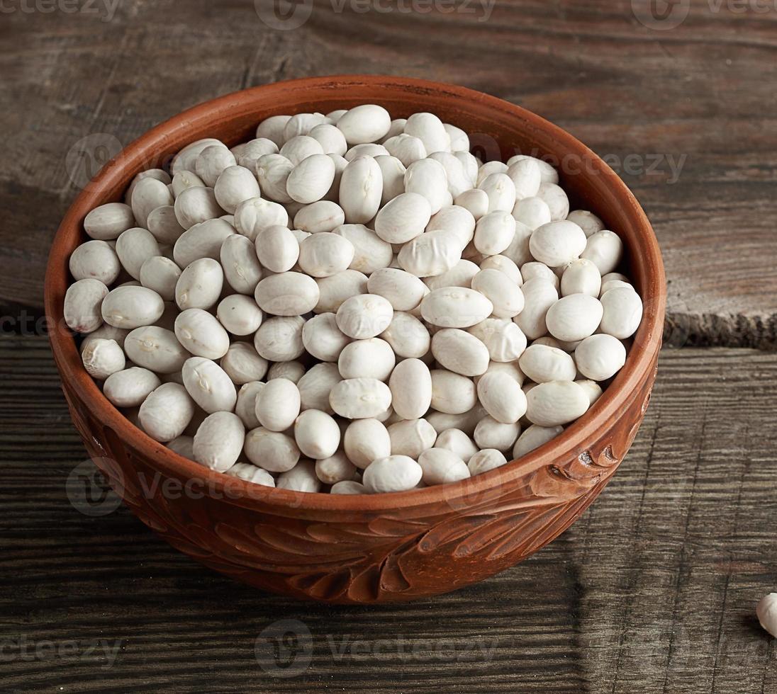 frijoles blancos redondos crudos en un plato sobre una mesa de madera. comida organica foto