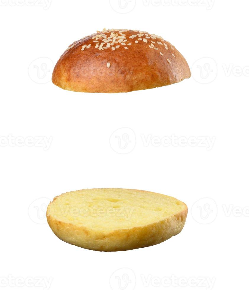 Two halves of a bun made of white wheat flour with sesame seeds isolated on a white background photo