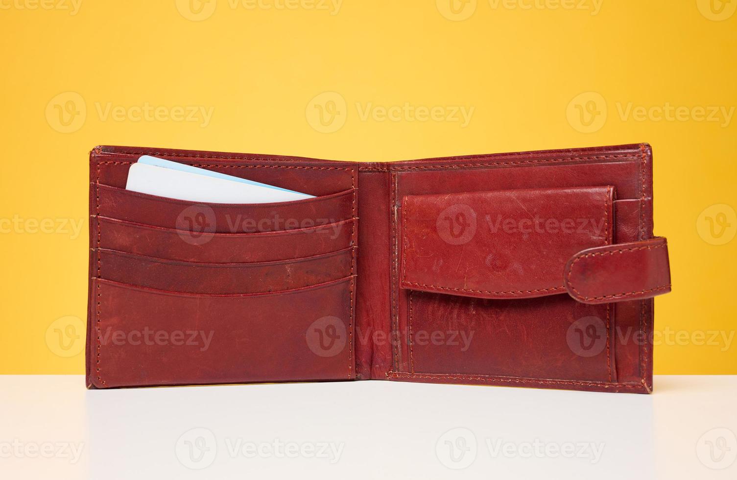 Open brown leather wallet with bank cards inside on a yellow background photo