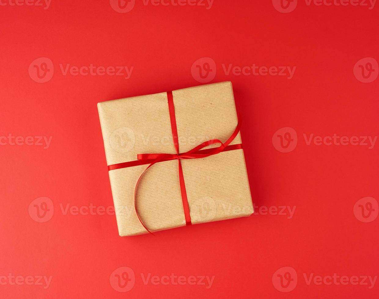 square box wrapped in brown kraft paper and tied with a red thin silk ribbon photo