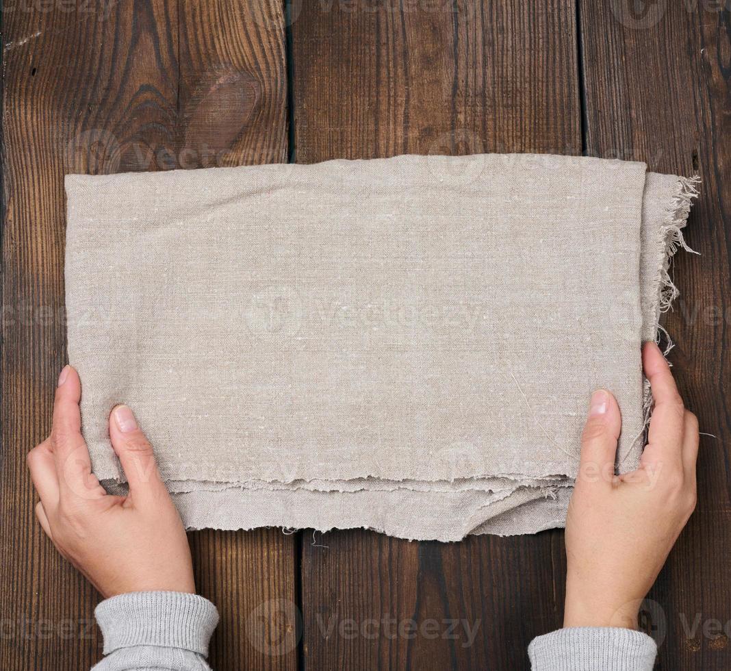 Gray linen kitchen towel on a brown table, top view photo