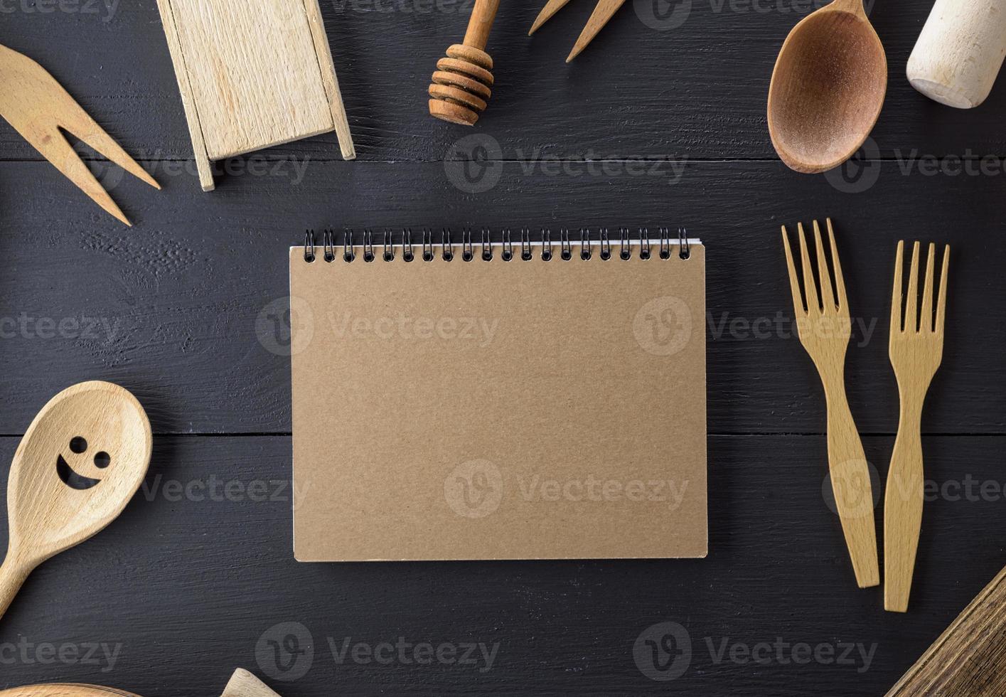 cuaderno abierto con páginas en blanco en medio de artículos de cocina de madera foto