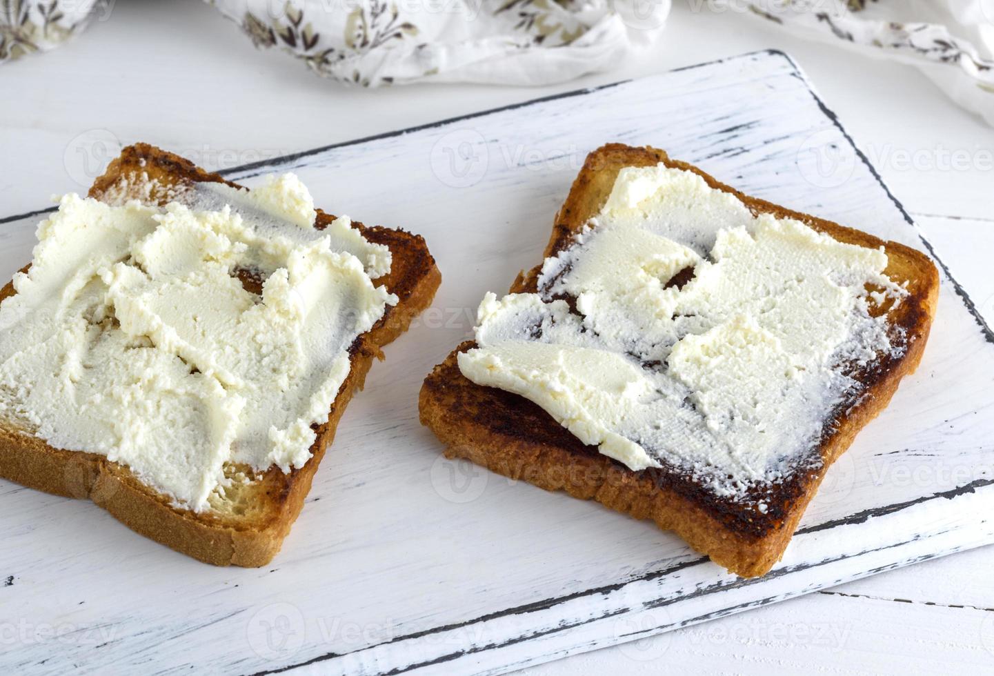 toasted bread with soft curd on a white wooden board photo