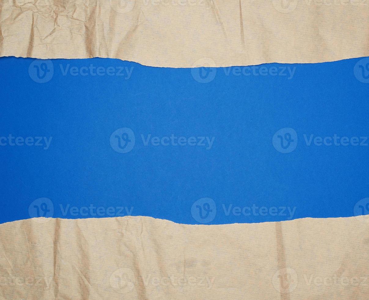 torn brown sheet of paper on a blue background, full frame photo