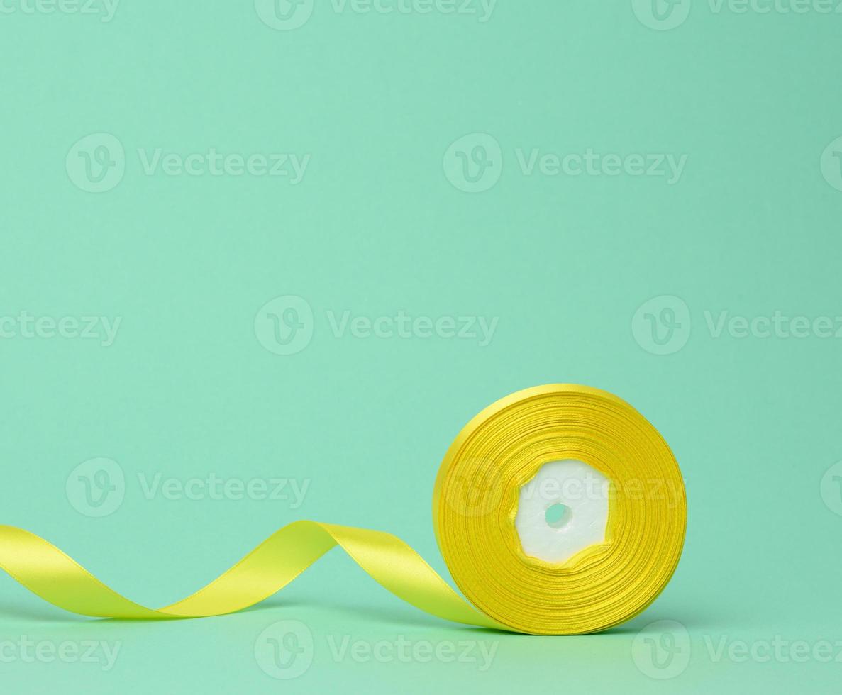 roll of yellow silk ribbon on a green background photo