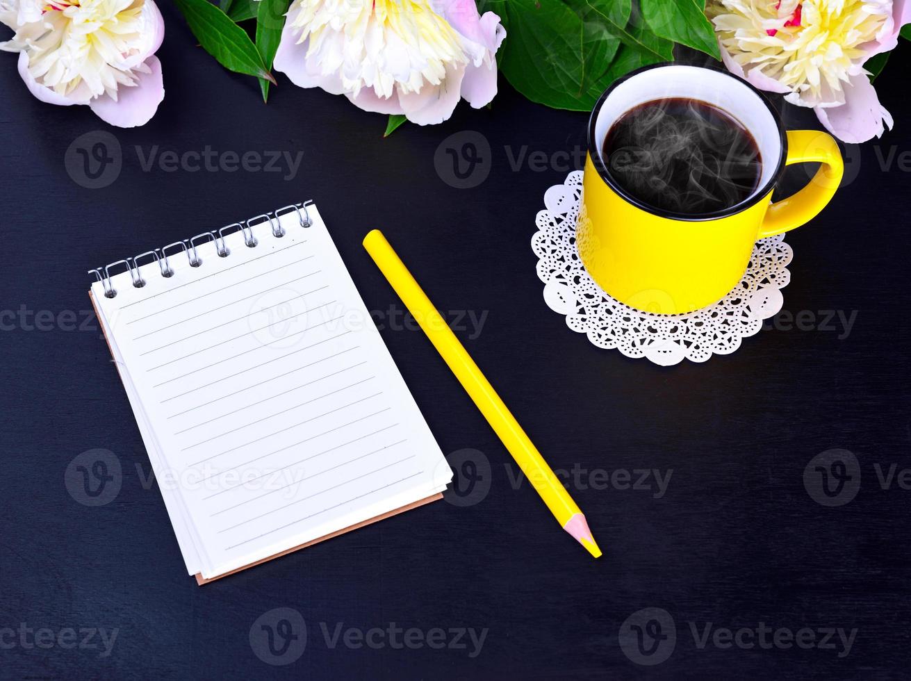 Empty notebook and yellow mug with hot coffee photo