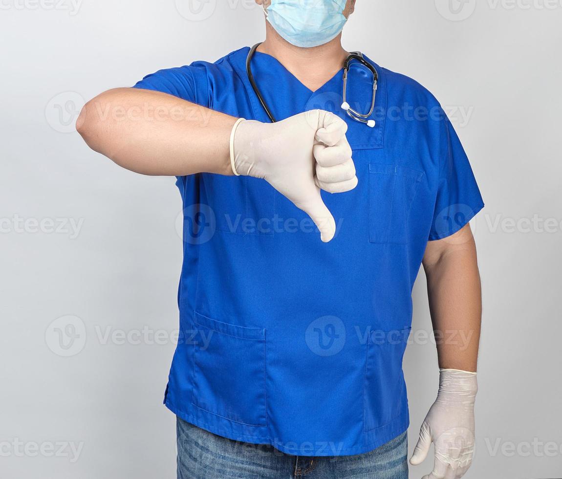 doctor in blue uniform and white  latex sterile gloves shows a gesture is bad photo