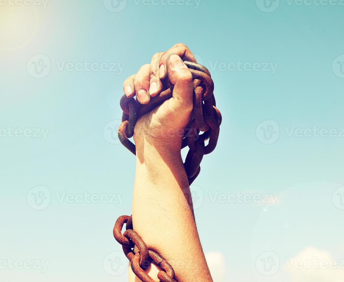 female hand is lifted up and bound by an iron chain photo