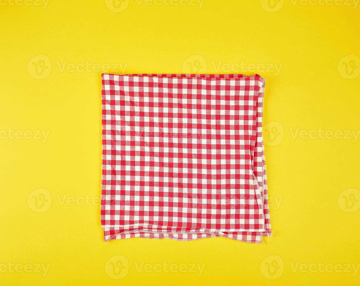folded red kitchen towel in a cage on a yellow background photo