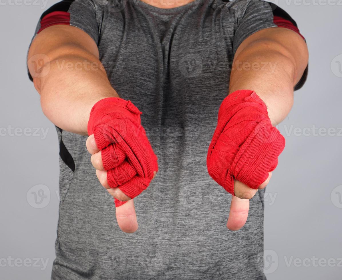 adult athlete in gray uniform and hands rewound with textile bandage shows gesture dislike photo