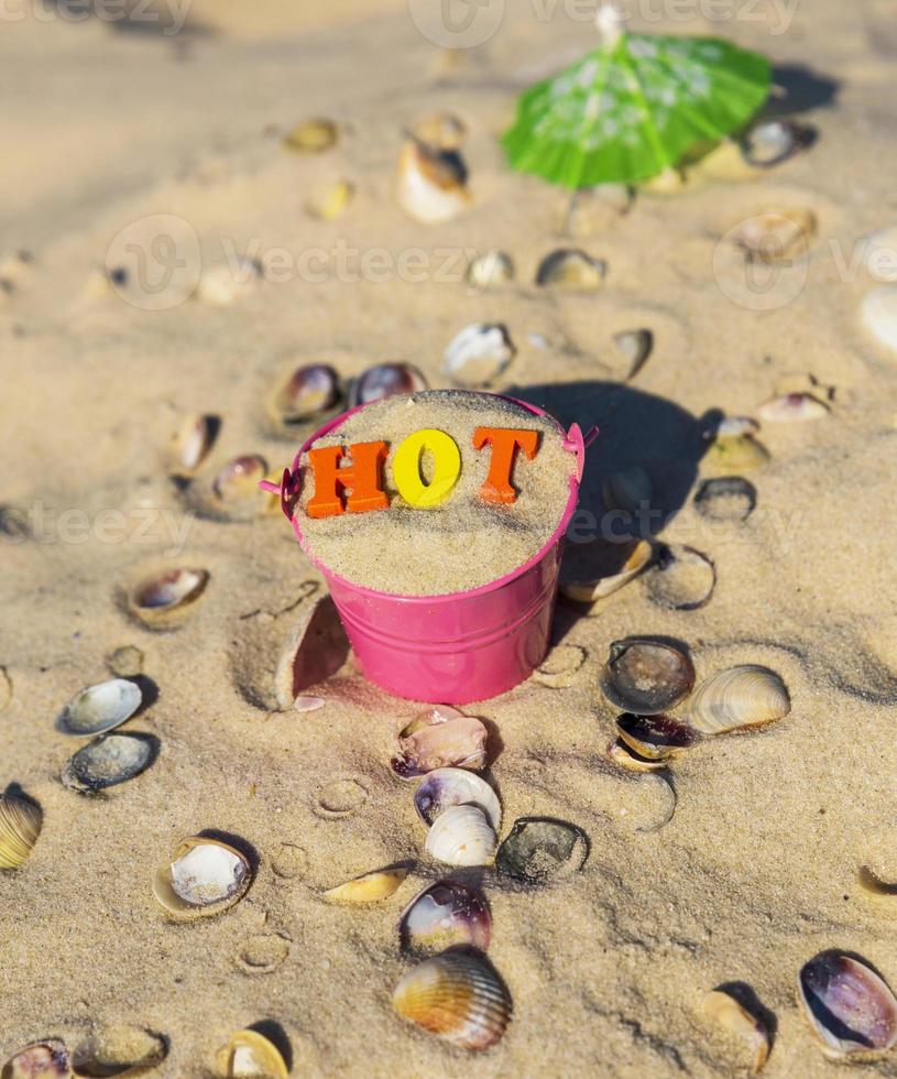 iron bucket with wooden colorful letters stands on the sand photo