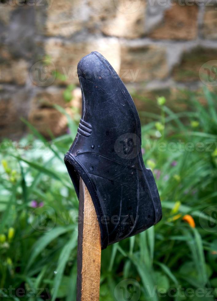 black rubber galosh hangs on a wooden stick photo