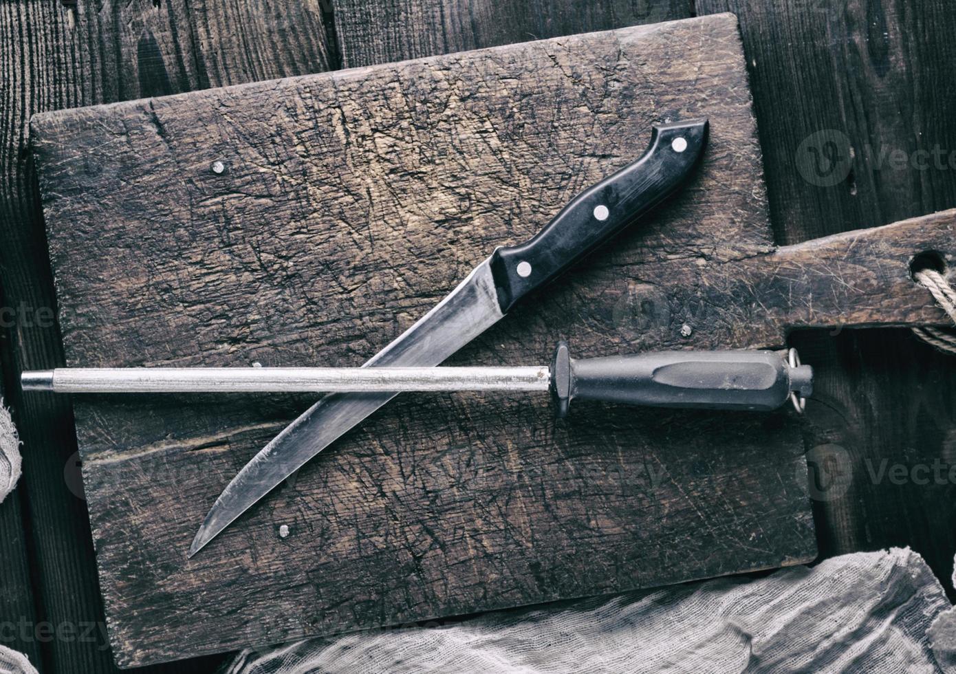 old knife and a sharpener on a brown wooden cutting board photo