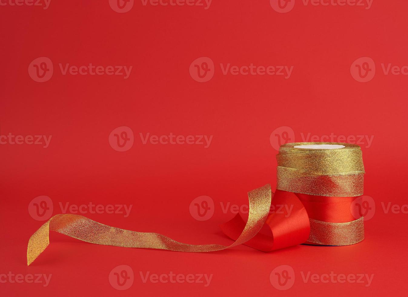 twisted golden and red silk shiny ribbon on a red background photo