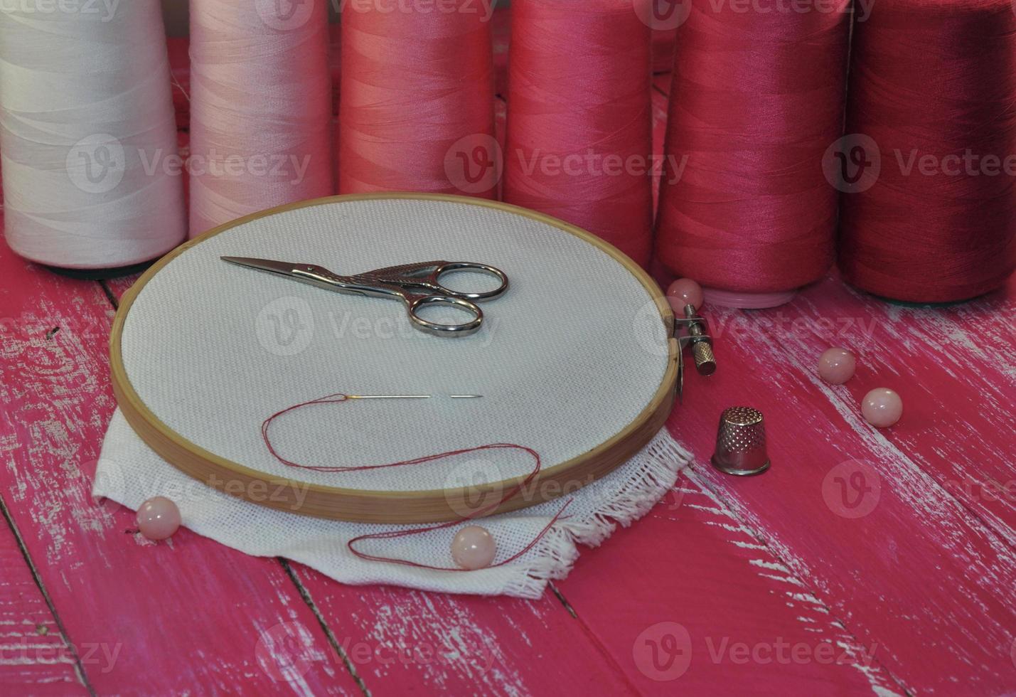 tools for needlework thread and red tones on a wooden table photo