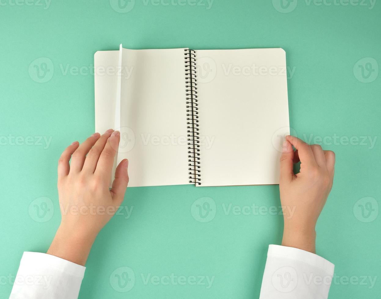 female hands hold open spiral notebook with clean white sheets photo