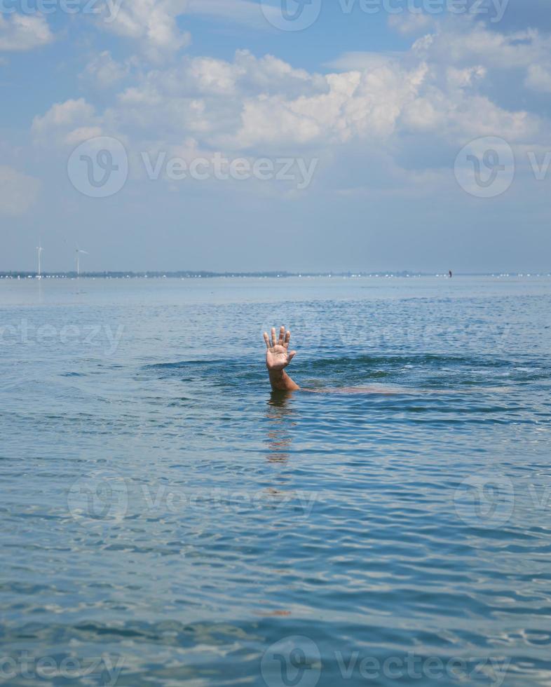 la mano sobresale del agua en medio del océano foto