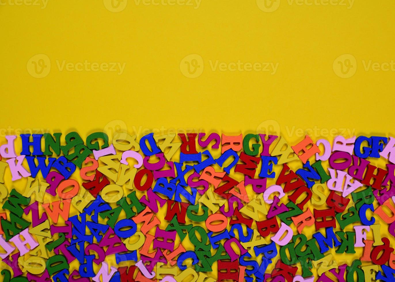Wooden multicolored letters of the English alphabet on a yellow surface photo