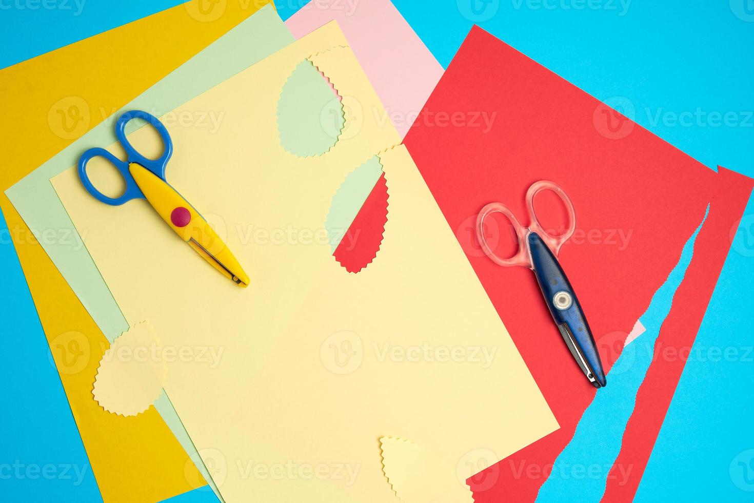 pair of plastic scissors and colored paper for cutting figures photo