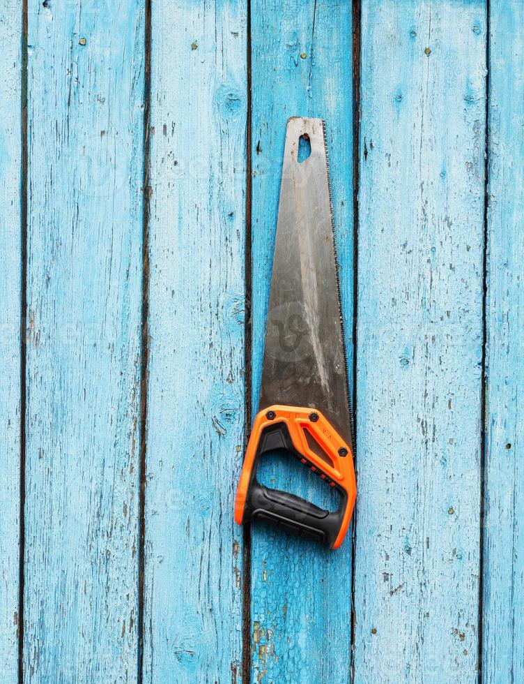 la sierra manual cuelga de un clavo en una pared de madera azul foto