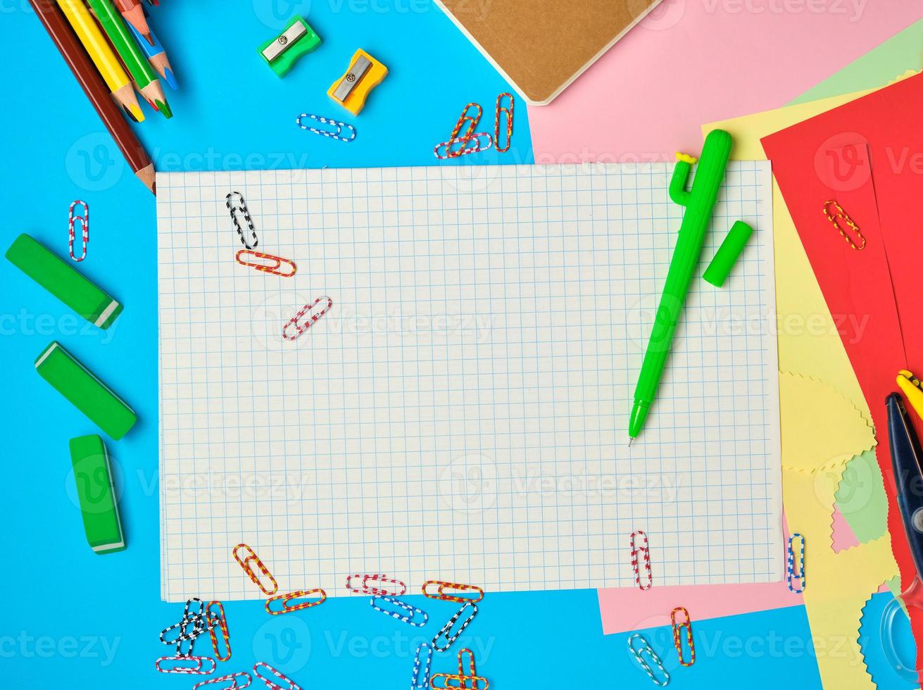 white squared paper from notebooks, wooden colored pencils, paper clips photo