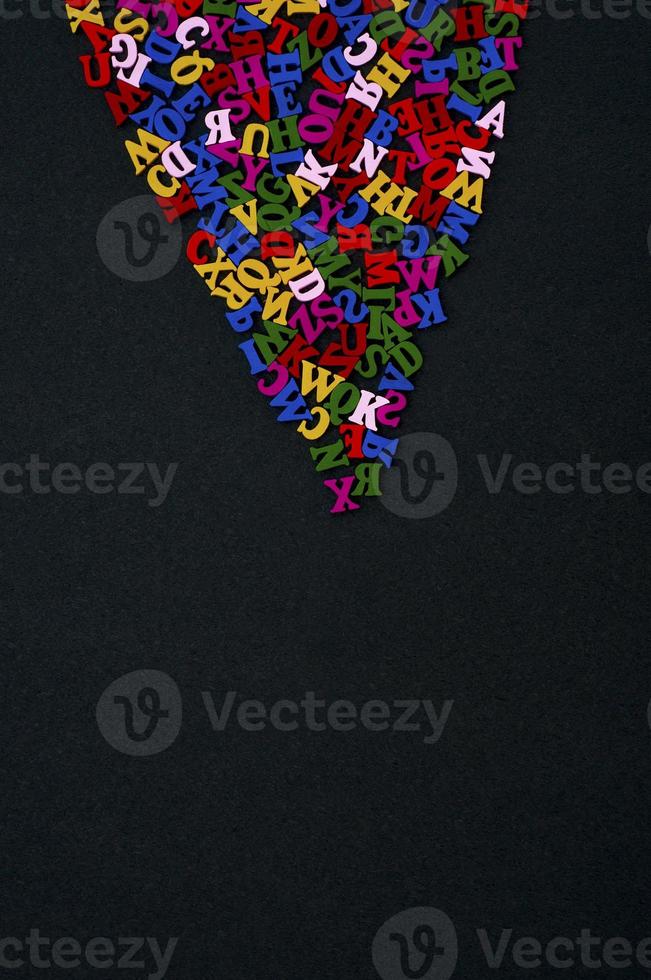 Colored wooden letters on a black surface, empty space from below photo
