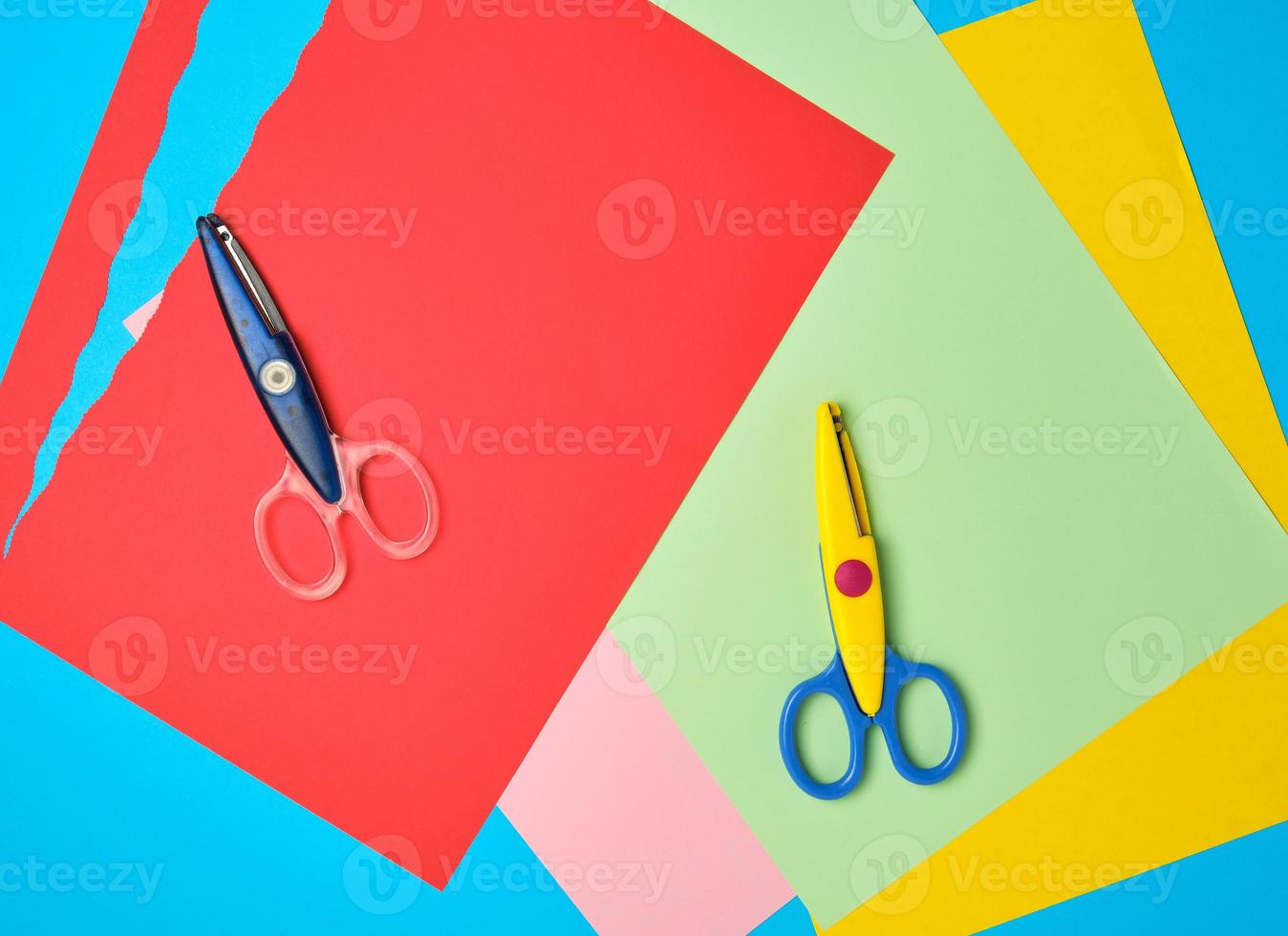 pair of plastic scissors and colored paper for cutting figures photo