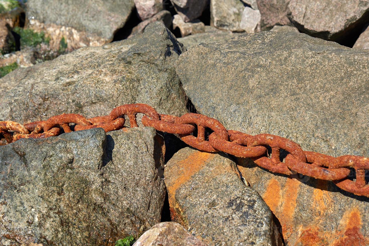 iron rusty ship chain in the midst of stones photo