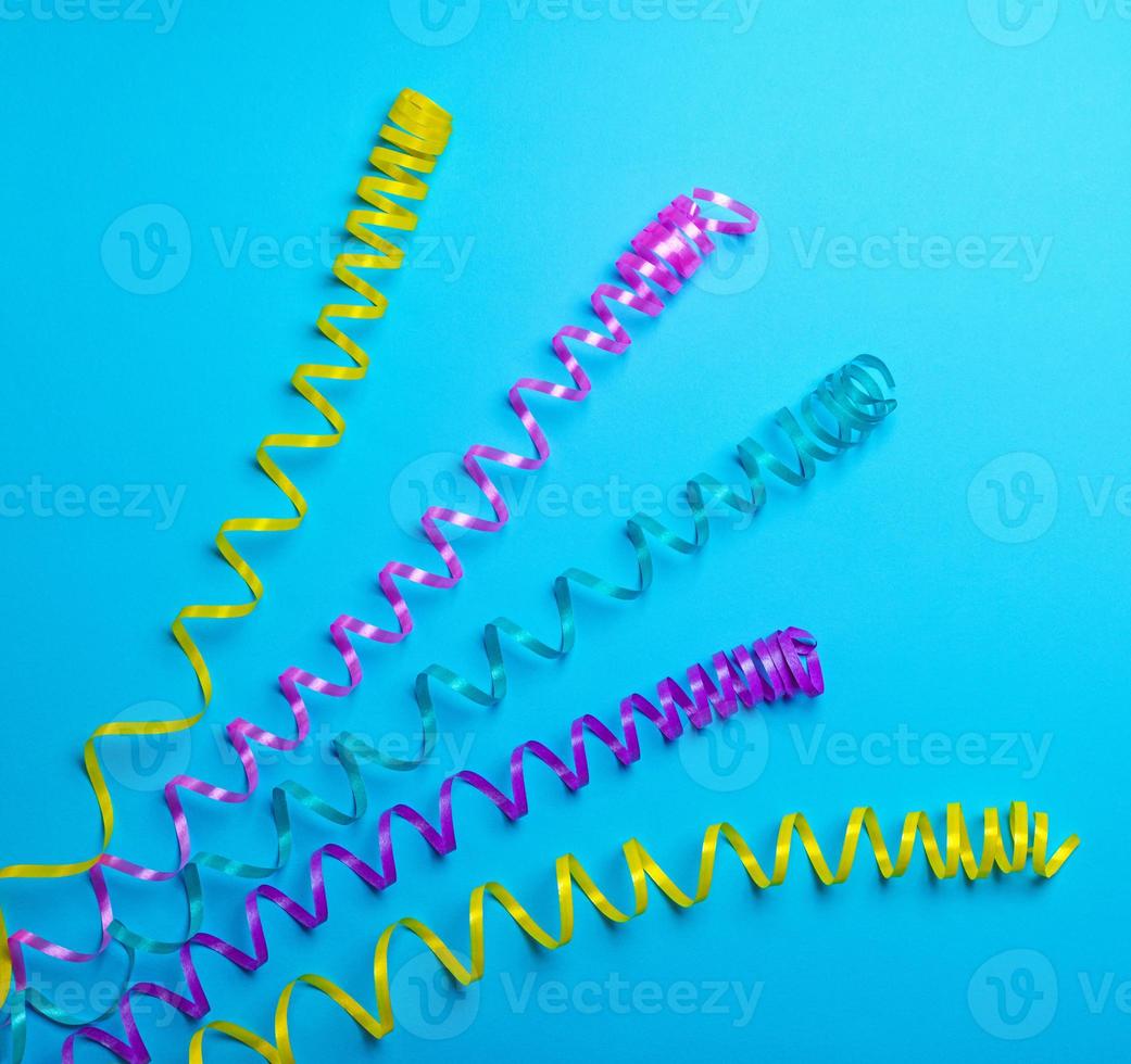 Multicolored paper serpentine stretched over a blue background photo