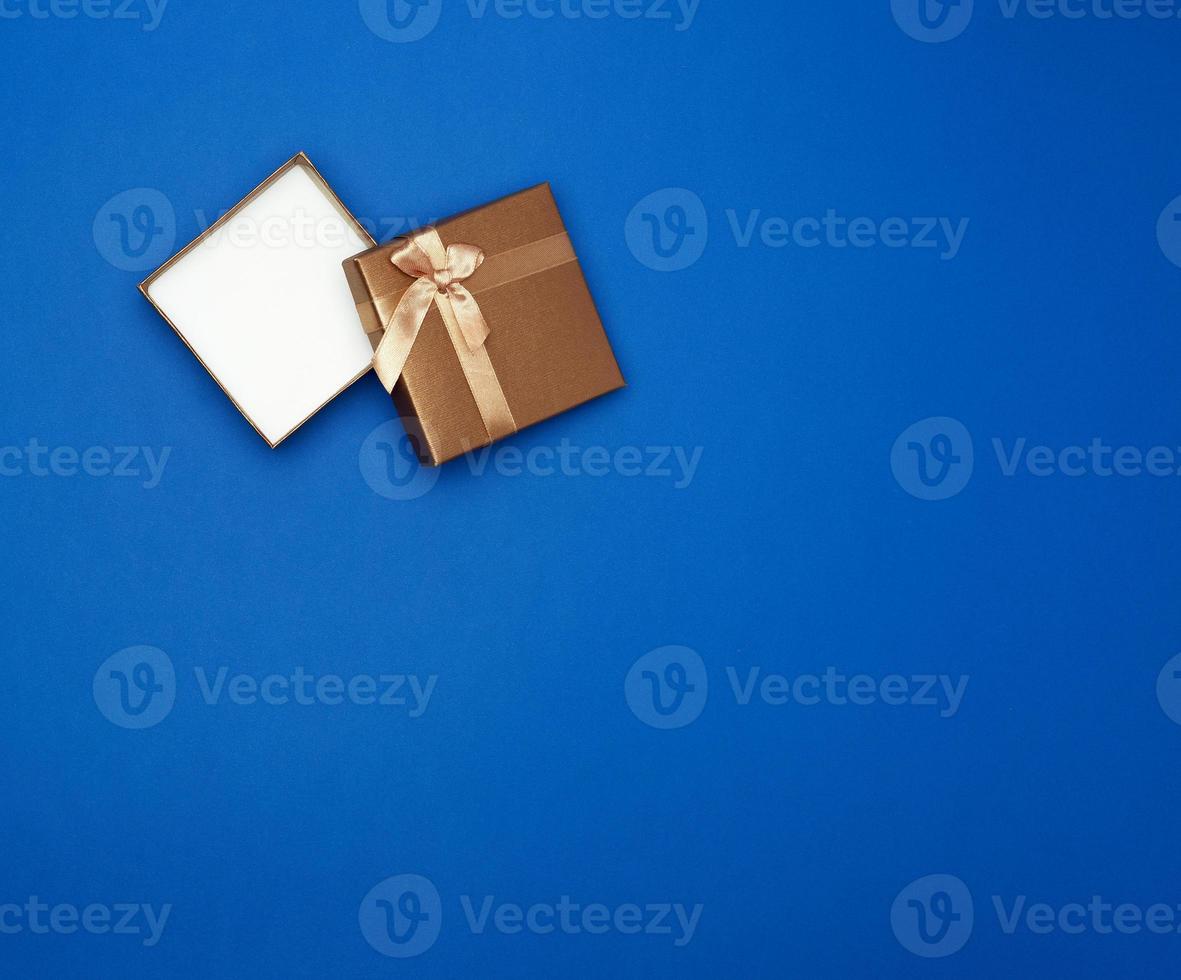 open brown square cardboard empty box, item lies on a blue classic background color photo