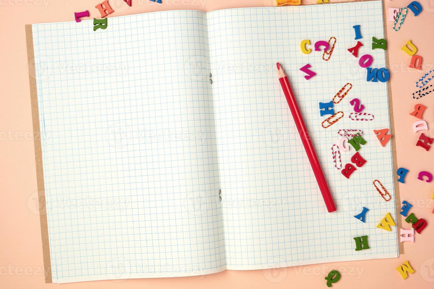 open checked notebook and red wooden pencil photo