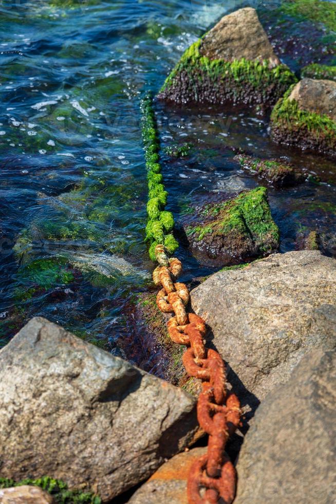 old rusty chain lies in the middle of the stones photo