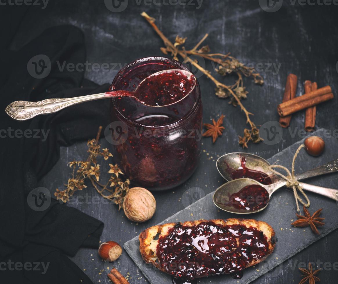 raspberry jam in a glass jar with an iron spoon photo
