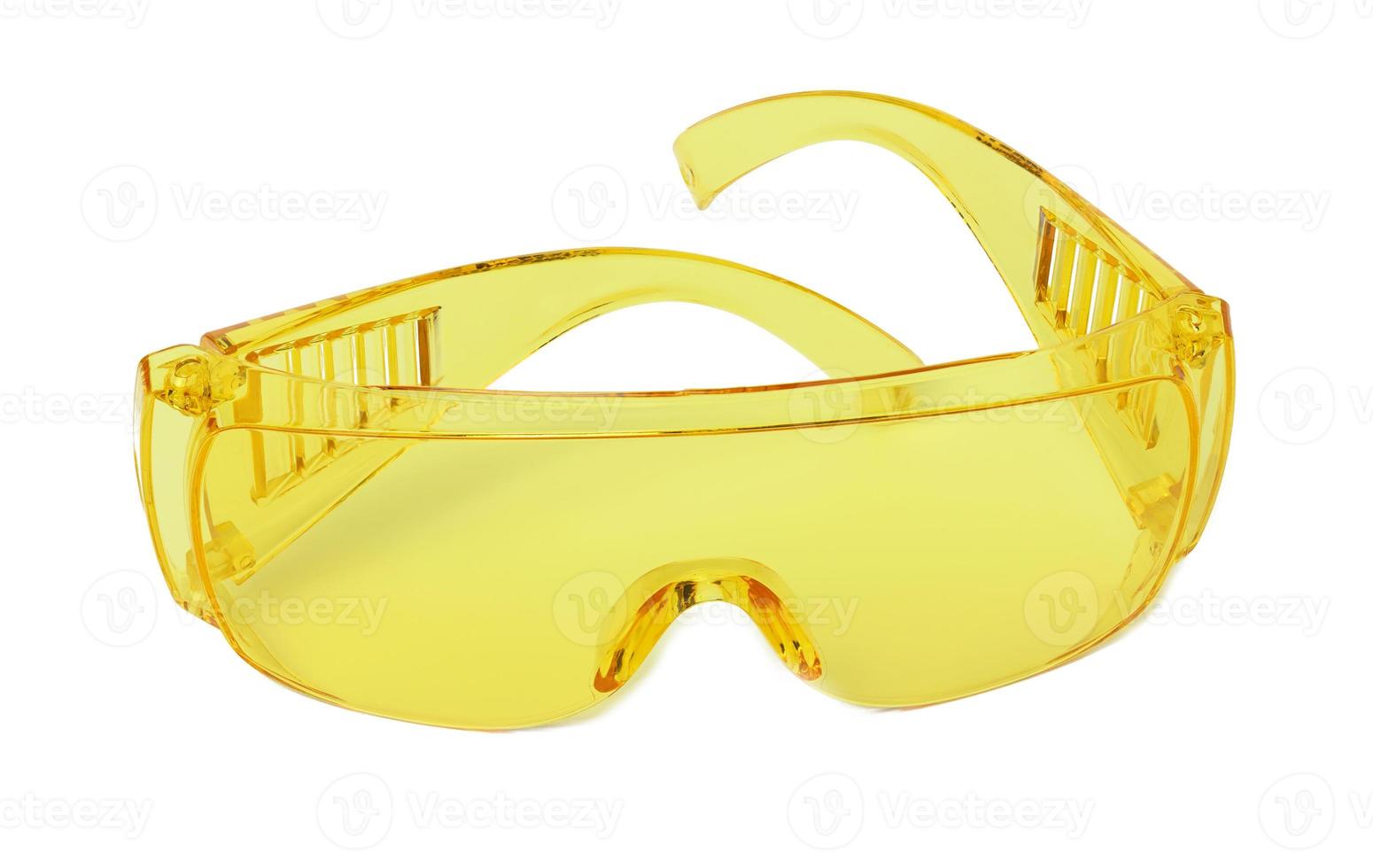 Yellow plastic protective goggles for workers on a white isolated background photo