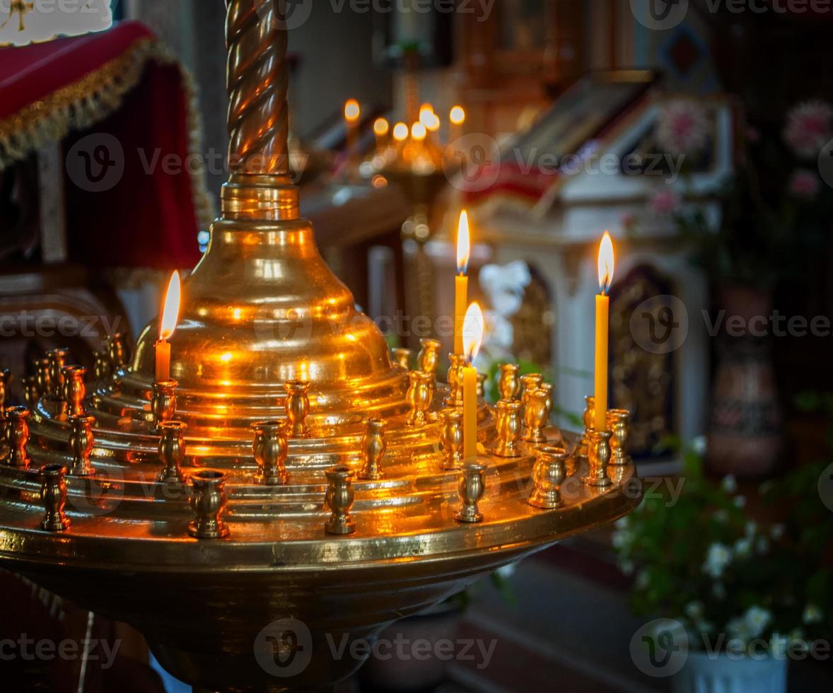 burning wax candles on a stand in the church photo