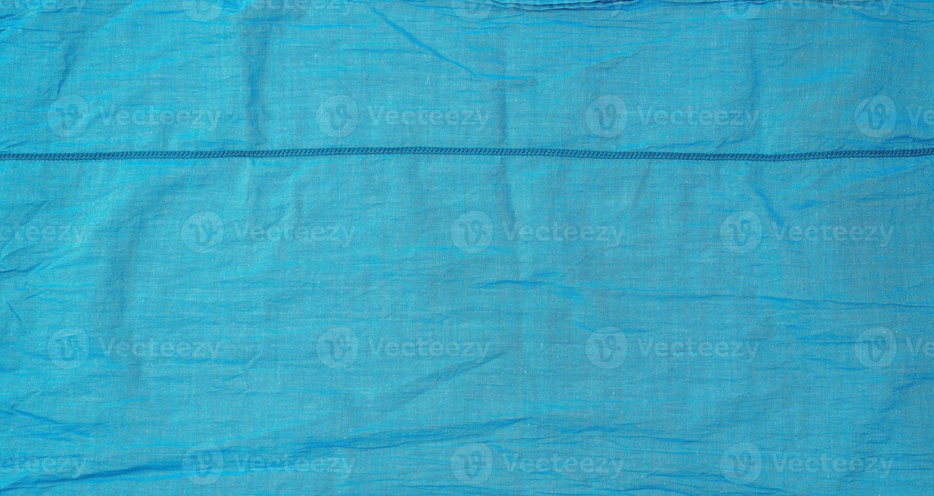 fragment of blue cotton fabric with a seam, full frame photo