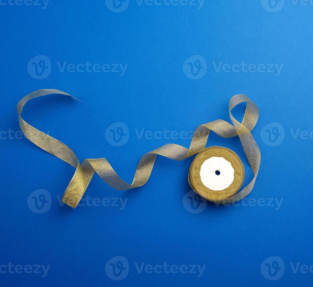 Shiny golden satin ribbon on a blue background. photo