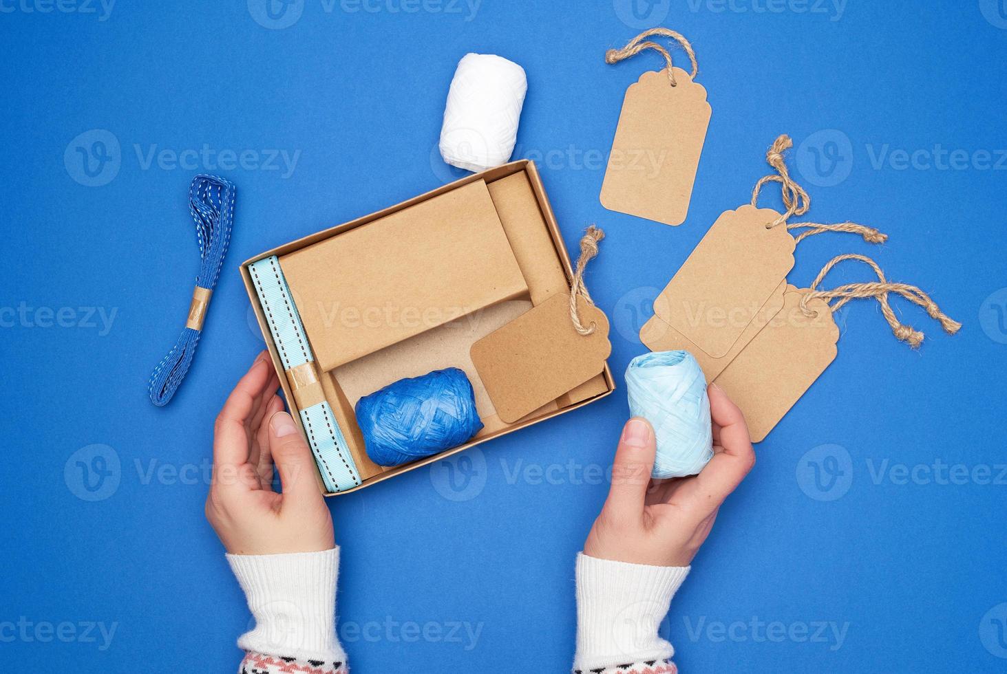 brown cardboard box with a set of festive decor for gift wrapping and two female hands photo