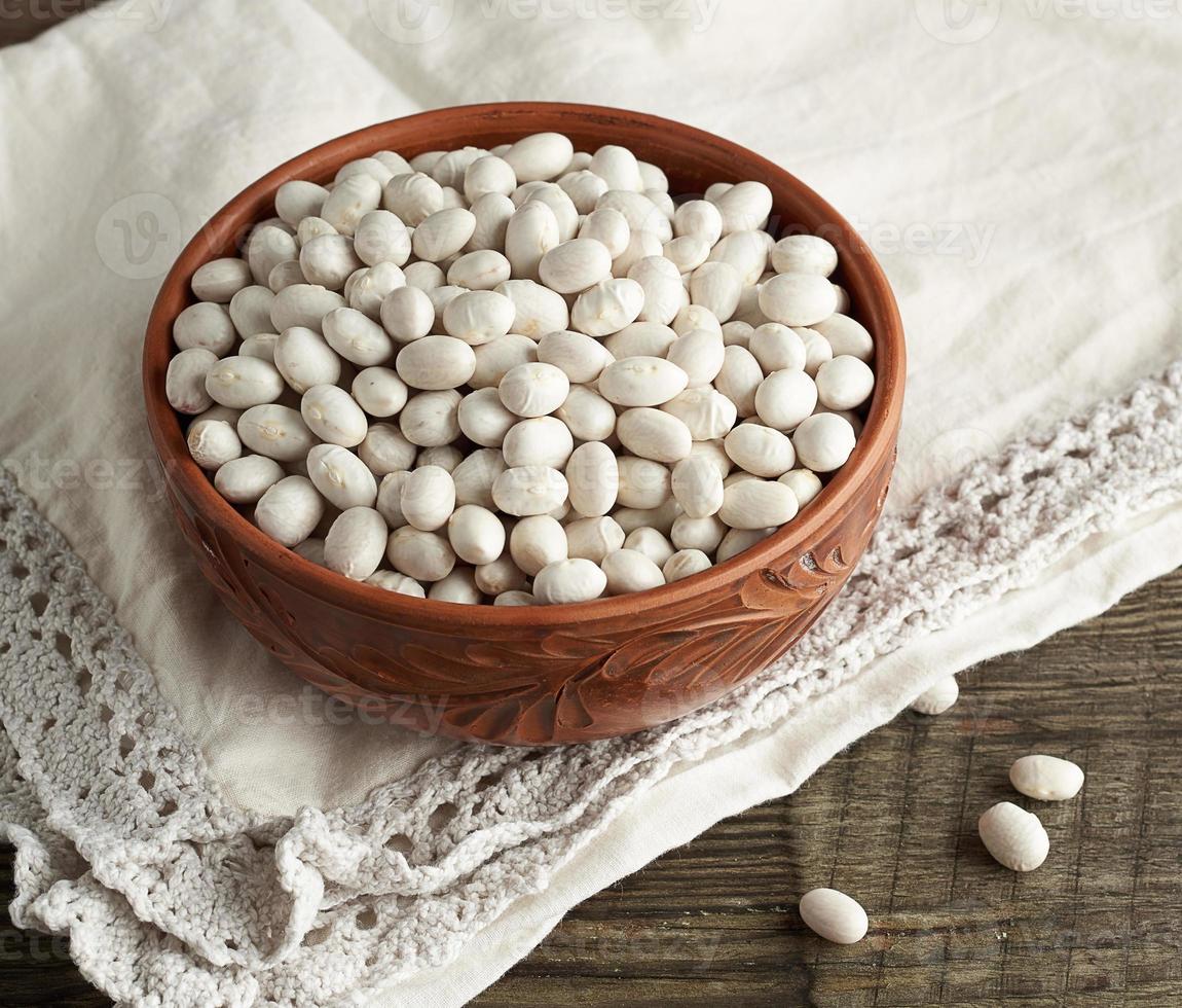 frijoles blancos redondos crudos en un plato sobre una mesa de madera. comida organica foto