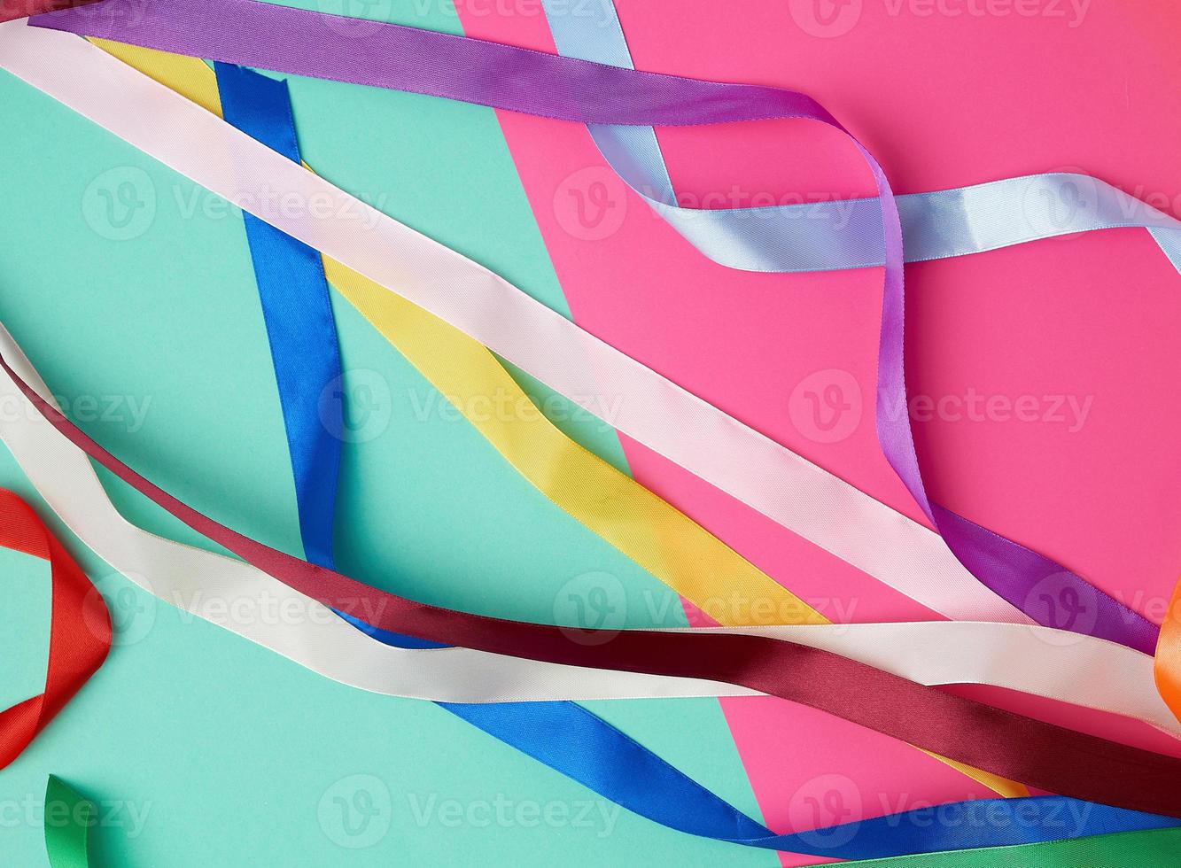 many silk multi-colored ribbons on a colored background photo
