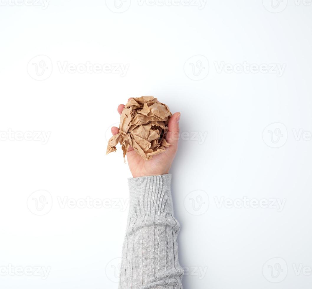 hand holds a crumpled sheet of brown paper on a white background photo