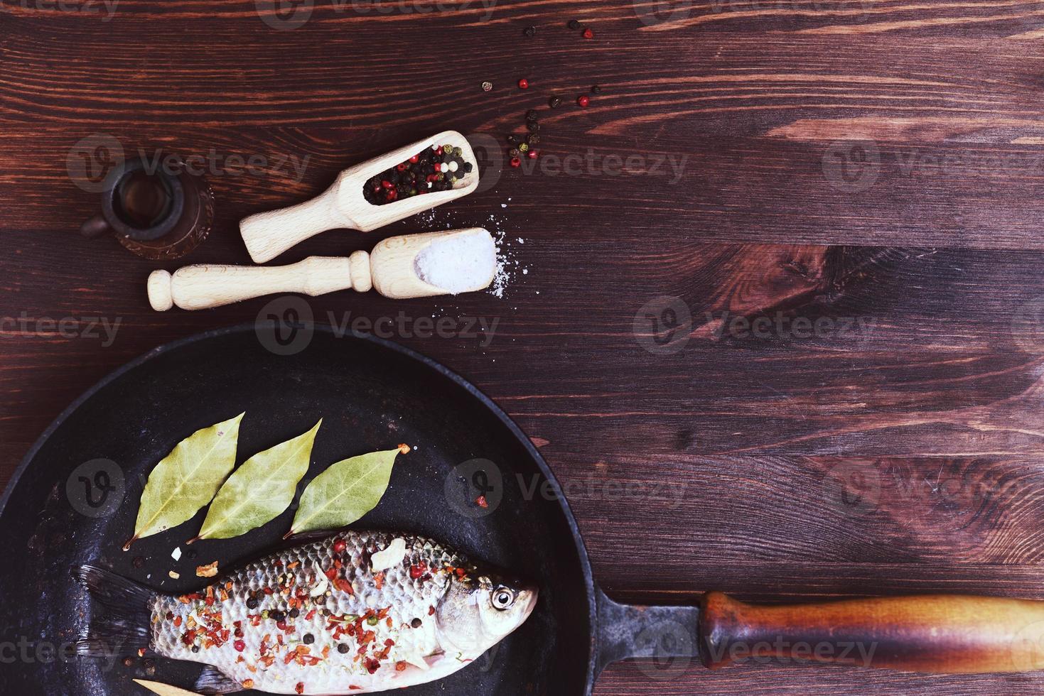 carpa de pescado de río con especias en una sartén negra de hierro fundido foto