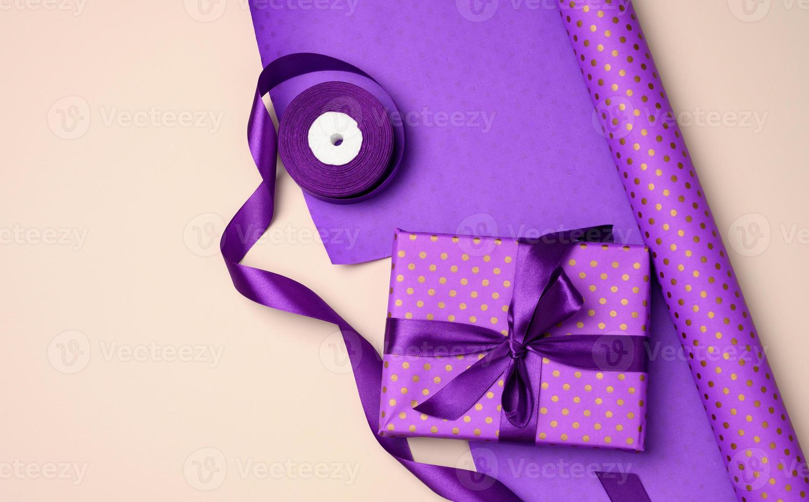gift boxes tied with purple silk ribbon on an beige background, top view photo