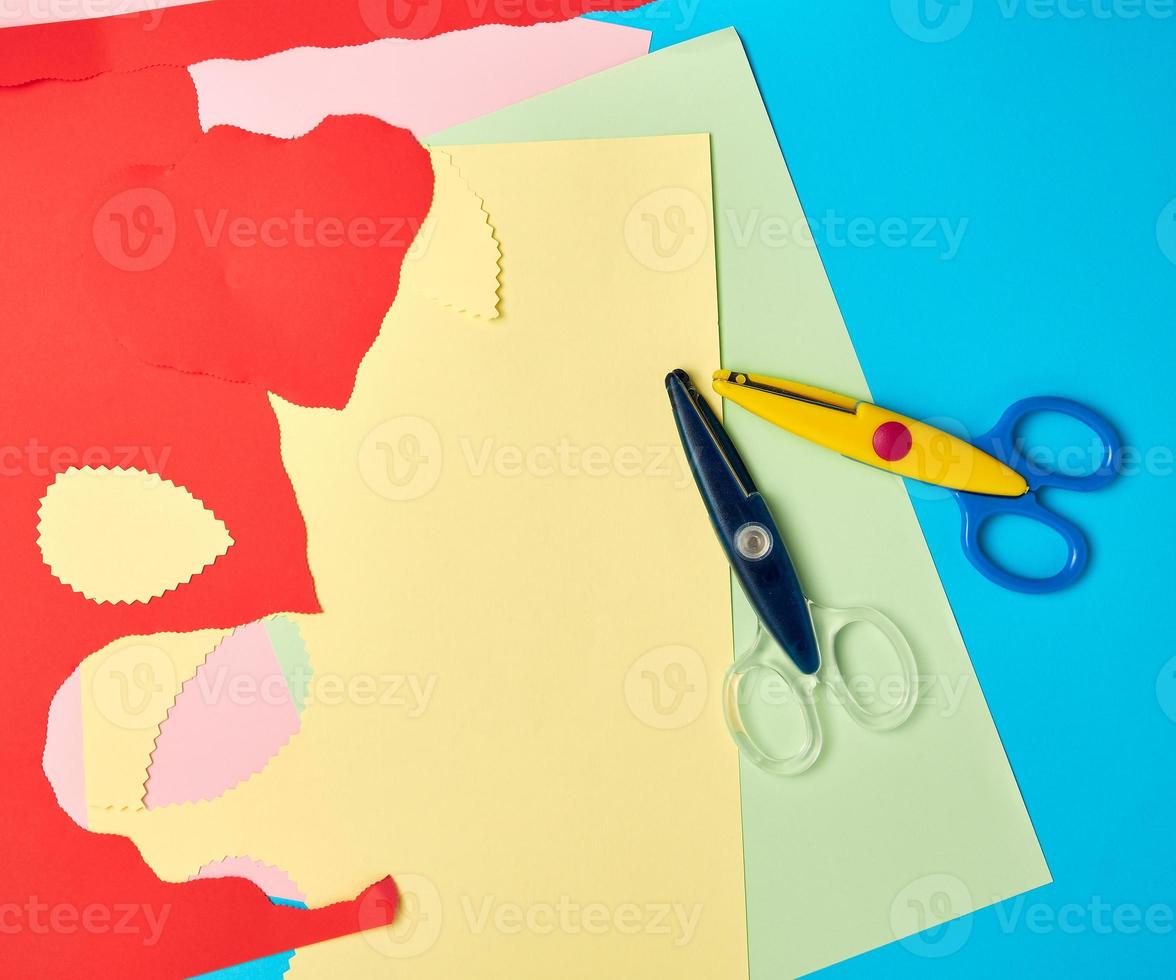 pair of plastic scissors and colored paper for cutting figures photo