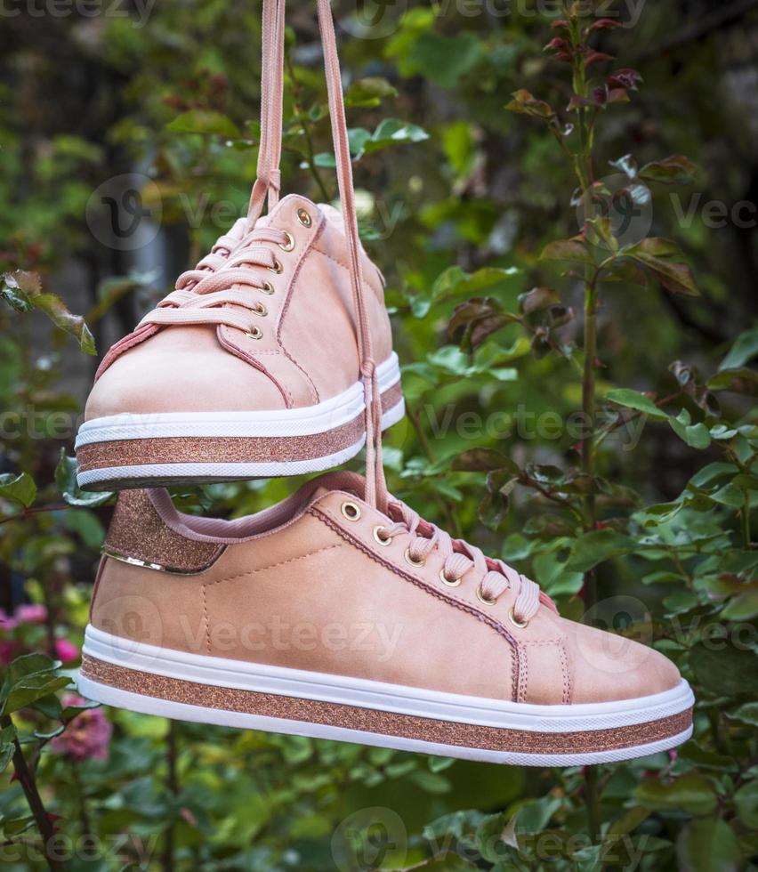 pair of female leather pink shoes hanging on a string photo