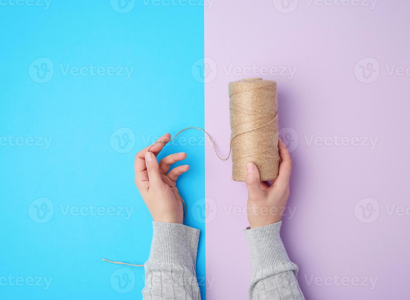female hands holding a skein with brown eco thread on a colorful background photo