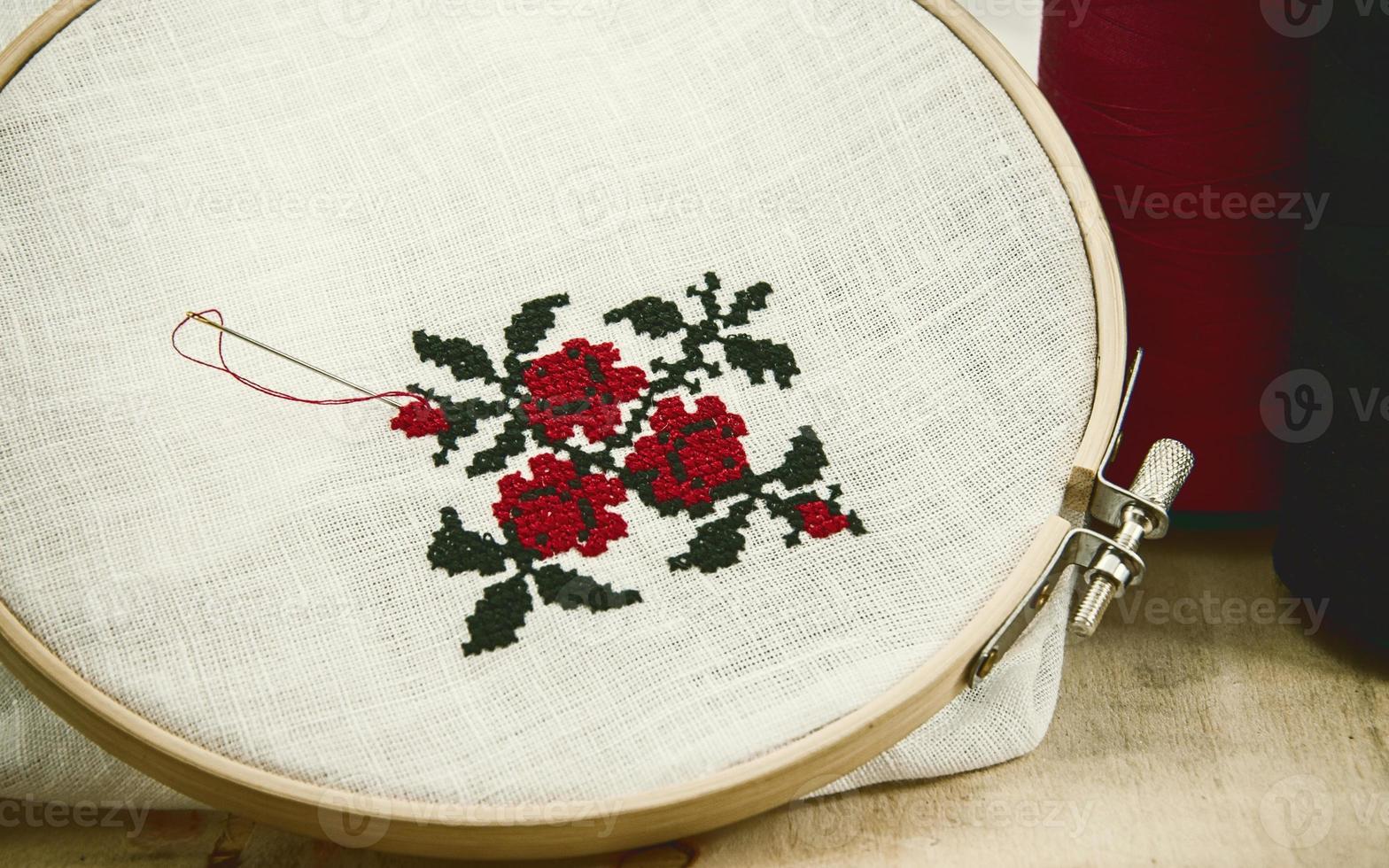 Hand embroidery cross-stitch flower ornament on a white fabric photo